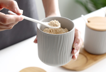 Using Ceramic Spoon To Scoop Superfood Powder Out Of Ceramic Jar With Wavy Pattern Pottery In Organic Seaside Style