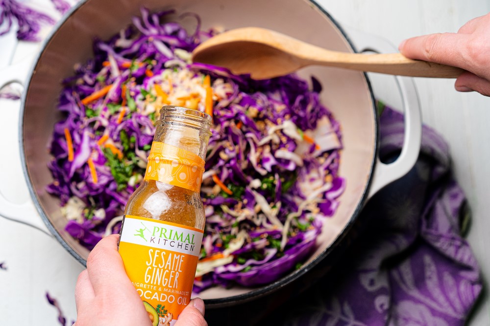 Pouring Sesame Ginger Vinaigrette Into 5 Minute No Cook Asian Slaw Primal Kitchen Recipe