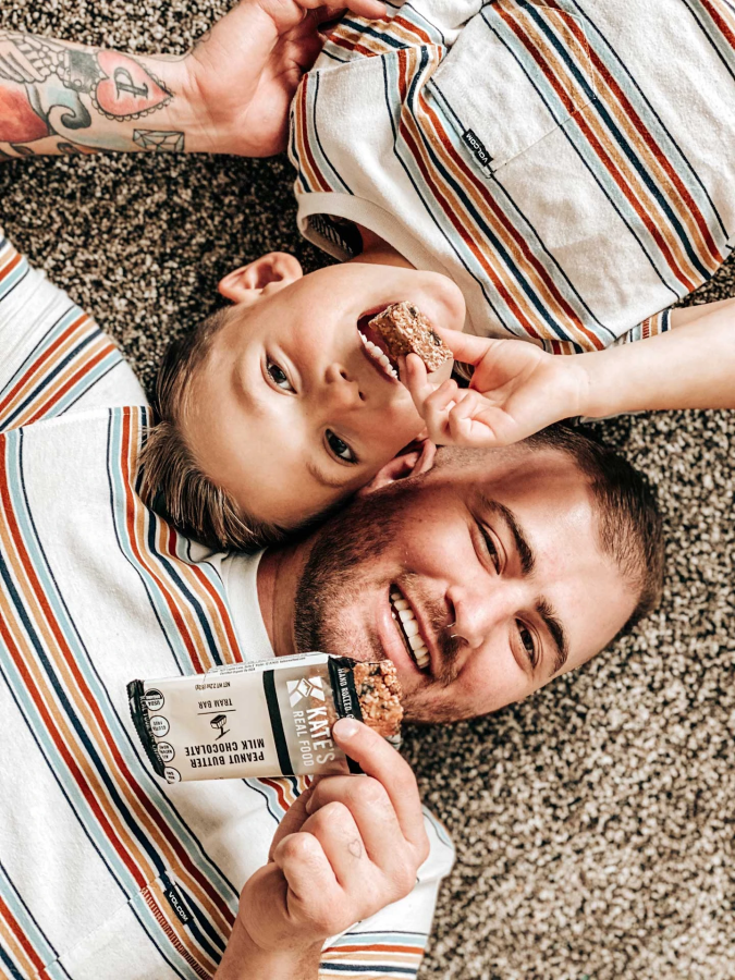 Happy Father And Son Snacking Healthy Granola Bars Kate's Real Food Peanut Butter Milk Chocolate Kid Approved Snack Food Bar