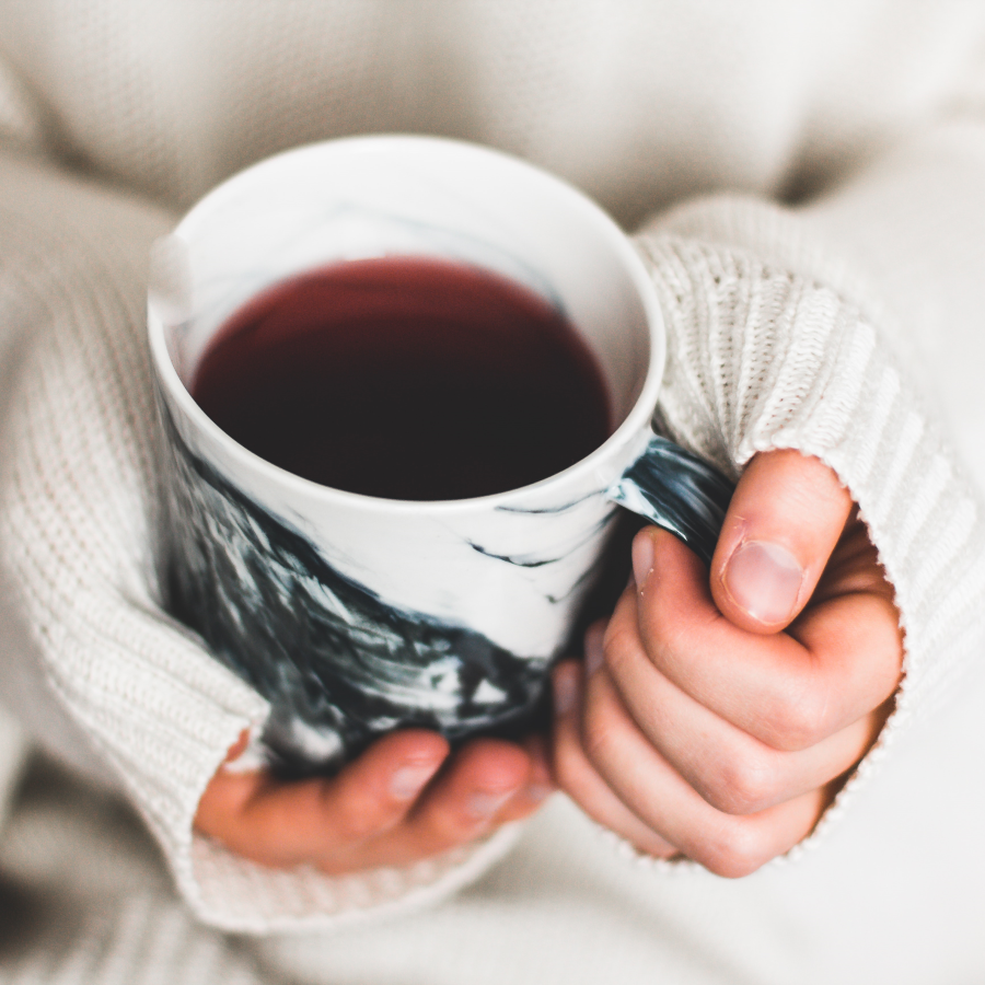 Hands Holding Black And White Marbled Mug Of Loose Leaf Steeped Organic Tea