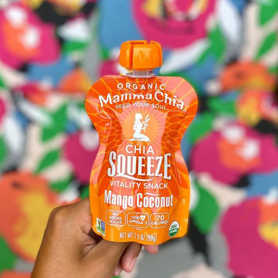 Hand Holding A Chia Seed Sqeeze Pack Mamma Chia Mango Coconut