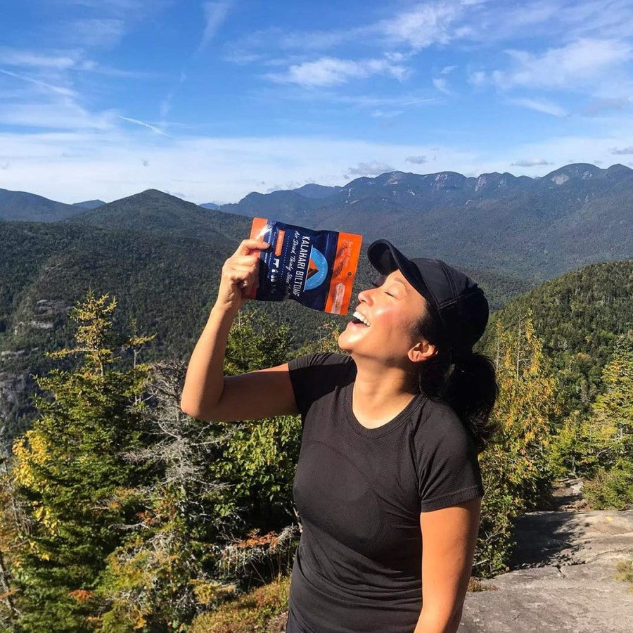 Happy Woman Outdoors Hiking And Snacking On Original Kalahari Biltong Jerky Like Beef Meat